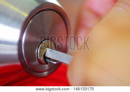 Closeup hands of locksmith using metal pick tools to open locked door.