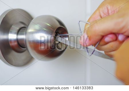 Closeup hands of locksmith using metal pick tools to open locked door.