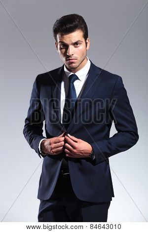 Elegant business man looking at the camera while closing his jacket.