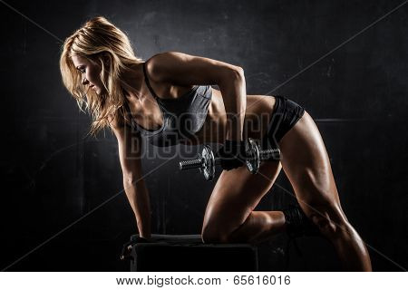 Brutal athletic woman pumping up muscles with dumbbells