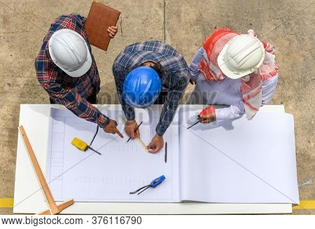 Top View Of Engineering Team In Site Manager Field Engineer And Foreman Looking At Construction Pape