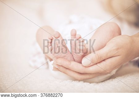 Newborn Feet. Sweet Baby In A Gentle Morning Light On The Bed. Bare Feet Of A Cute Newborn Baby In W