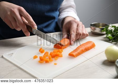 Woman Cutting Boiled Carrot At White Wooden Table, Closeup. Cooking Vinaigrette Salad