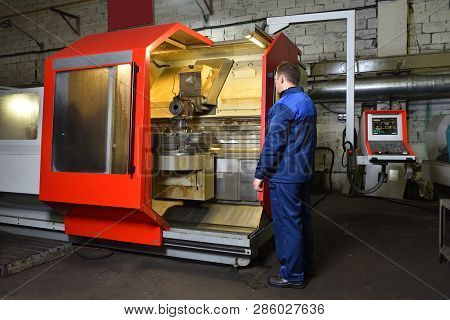 The Worker In Blue Workwear, The Operator Of The Cnc Machine, Oversees The Process And Controls It. 