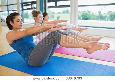 Frauen tun Boot stellen in Yoga-Kurs im Fitness-studio