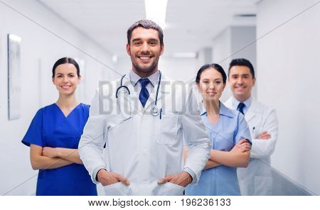 clinic, profession, people, health care and medicine concept - happy group of medics or doctors at hospital corridor