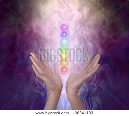 Working with the Seven Major Chakra Energy Vortexes  -  female healer's hands either side of seven chakra vortexes on an ethereal dark to light misty swirling energy field