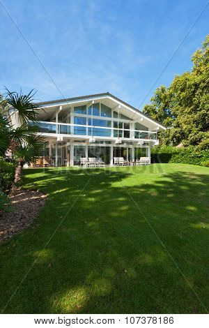 Facade of a beautiful house with green garden, summer day 