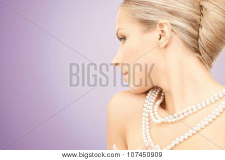 beauty, luxury, people, advertisement and jewelry concept - beautiful woman with sea pearl necklace or beads over violet background