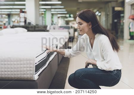 A Woman Chooses A Mattress In A Store. She Sits Next To Him And Examines Him