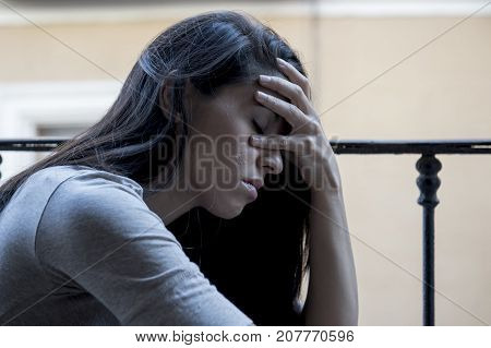 young sad and desperate Latin woman sitting at home balcony looking destroyed and depressed suffering depression feeling lonely unhappy and hopeless in mental health and crisis concept