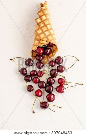 Ice Cream Cone Filled With Cherries On A Light White Concrete Background.