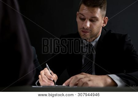 Interrogator Taking Note While Interviewing Suspect In The Interrogation Room