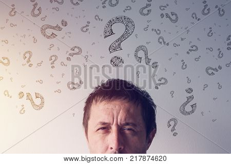 Question mark looking for answers. Perplexed man with scribbled interrogation point symboles around his head.