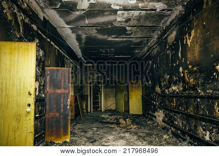 Burned by fire interior of old building. Charred ash walls, doors and damaged furniture, dark toned