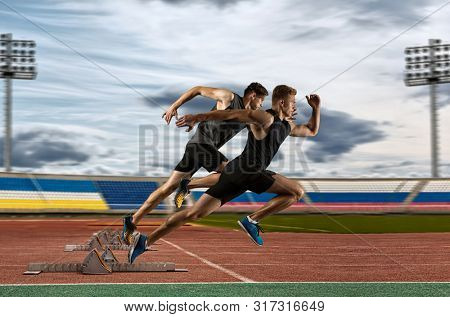 Man sprinter leaving starting blocks on the athletic track 