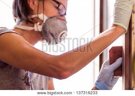 Woman In Gloves Sanding Frame Around Door