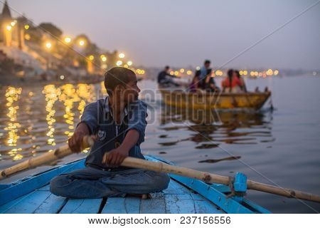 VARANASI, INDIA - MAR 13, 2018: Boatmen on the Ganga river at night. Varanasi is one of the most important pilgrimage sites in India and is one of the 7 sacred cities of Hinduism.