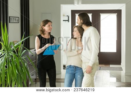 Friendly Realtor Or Landlord Talking Showing Modern Luxury House For Sale To Young Couple Customers,