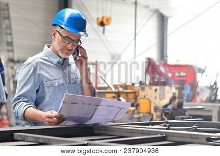 Metallurgy engineer talking on phone in factory