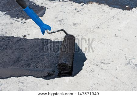 Worker covered surface bitumen primer for improving adhesion during surfacing rolled waterproofing during the installation of isolation on industrial or household objects