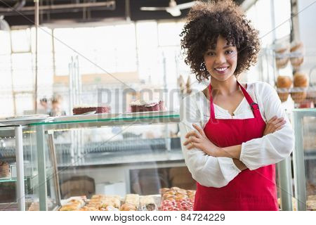 Pretty employee posing with arms crossed at the bakery