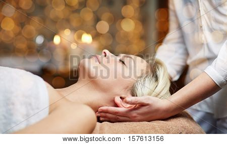 people, beauty, spa, healthy lifestyle and relaxation concept - close up of beautiful young woman lying with closed eyes and having head massage in spa