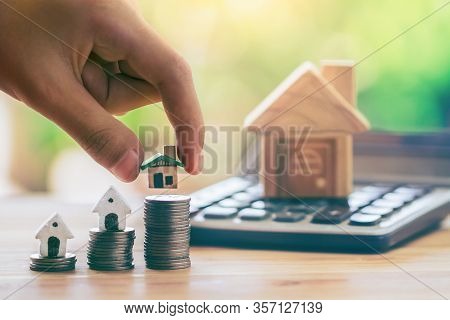 House On Coins And House Put On Calculator. Man's Hand Putting Home. Planning Savings Money