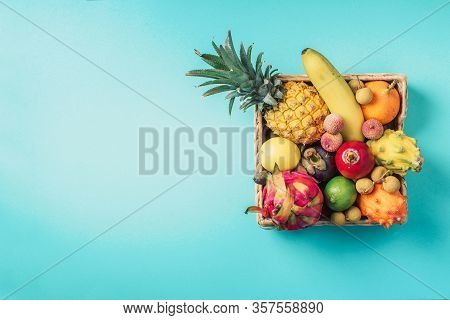 Tropical Fruits On Blue Background. Rattan Box Full Of Exotic Thailand Fruits - Pineapple, Pitahaya,