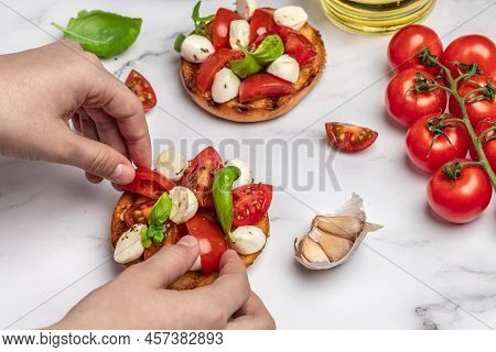 Woman Hands Preparing Caprese Bruschetta In The Kitchen. Delicious Breakfast Or Snack, Clean Eating,