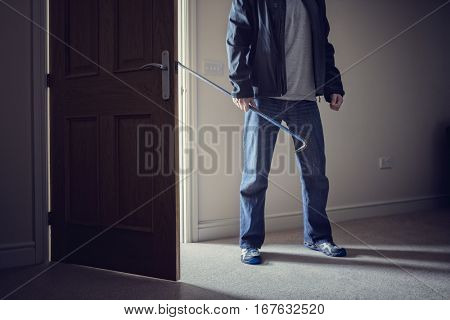 Burglar committing a burglary crime in a house with a crowbar