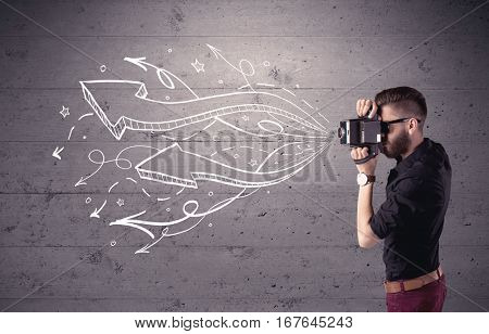 A hipster guy opening his point of view through looking a vintage camera concept with illustratied drawn arrows on urban wall