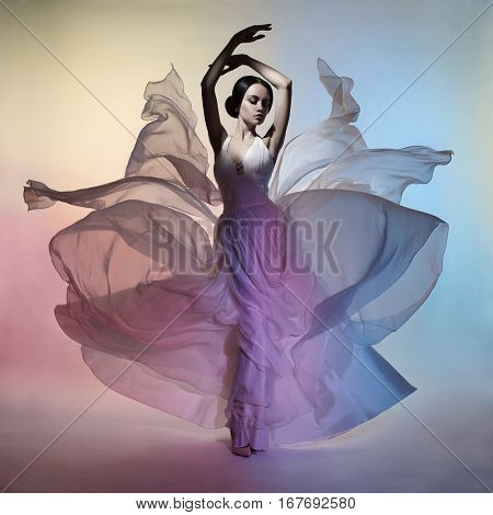 Art fashion studio photo of beautiful elegant woman in blowing dress. Flying dress. Freedom concept
Drawing of colors. Light and color effects. Fashion style of flowing dress