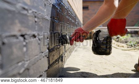 Applying Protective Waterproofing To The Foundation Of The House. Foundation Waterproofing With Bitu