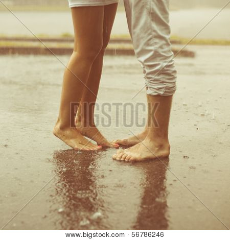 A loving young couple hugging and kissing under a rain. Two lovers, man and woman barefoot in the shower. Summer in love