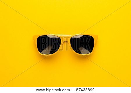 studio shot of yellow sunglasses. summer is coming concept with yellow sunglasses. sunglasses on yellow background. sunglasses on seamless background. top view of sunglasses