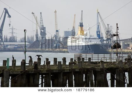 The derelict old pier at Southampton docks with cruise ship, dockside and cranes behind.