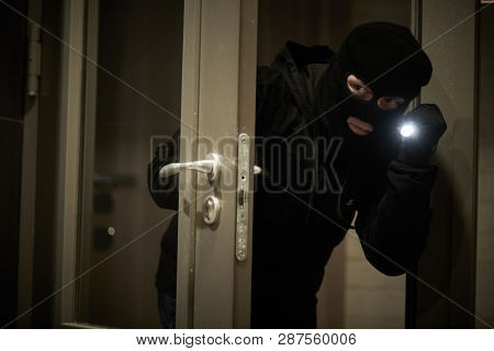 Burglar thief in mask. break-in of an apartment.