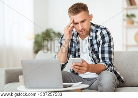 Unpleasant Message Concept. Portrait Of Upset Depressed Guy Using His Cellphone, Disappointed And Sh