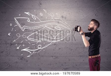 A hipster guy opening his point of view through looking a vintage camera concept with illustratied drawn arrows on urban wall