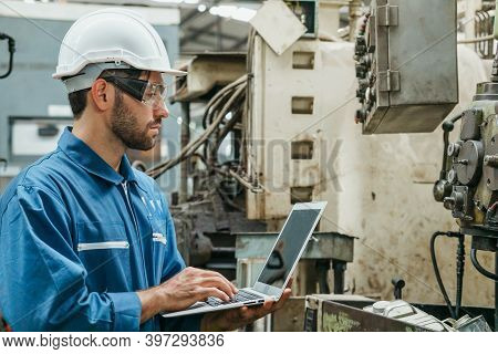 Factory Engineer Or Mechanical Worker Wearing White Safety Helmet Holding Laptop And Checking On Pro