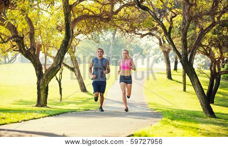 Athletic couple running together. Sport runners jogging on park trail in the early morning.  Healthy lifestyle fitness concept