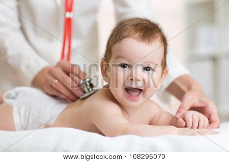 Pediatrician doctor examines baby with stethoscope checking heart beat.