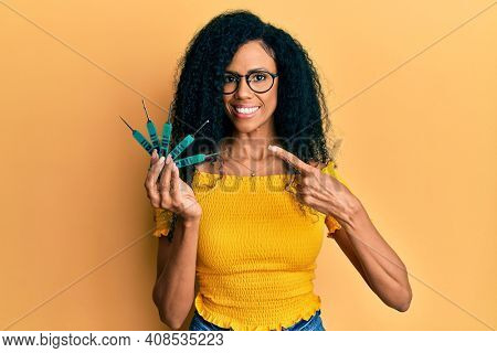 Middle age african american woman holding picklock to unlock security door smiling happy pointing with hand and finger 