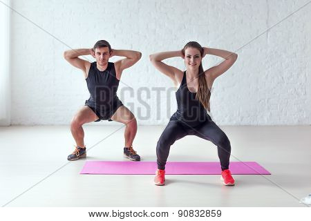 Fitness man and woman exercising squat exercise hands behind head concept sport, training, warming u