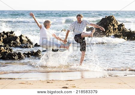 lovely senior mature romantic couple on their 60s or 70s retired walking happy and relaxed on beach sea shore in romantic aging together and retirement husband and wife lifestyle concept