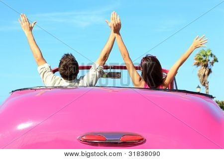 Liberdade - feliz casal livre no carro dirigindo carro de retro vintage rosa torcendo alegre com os braços levantar