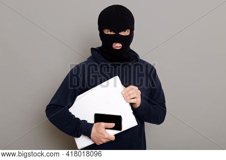 Satisfied Man Robber Steals Laptop Beech And Phone, Being Dressed In Robber Mask And Black Turtlenec