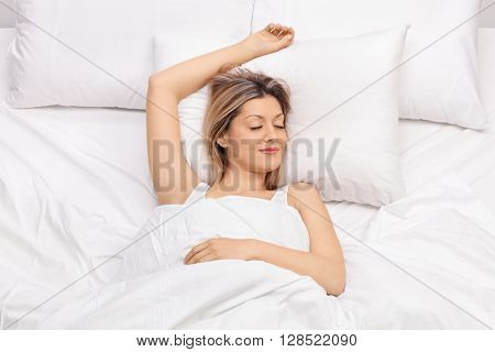 Joyful young woman sleeping on a comfortable bed and smiling 