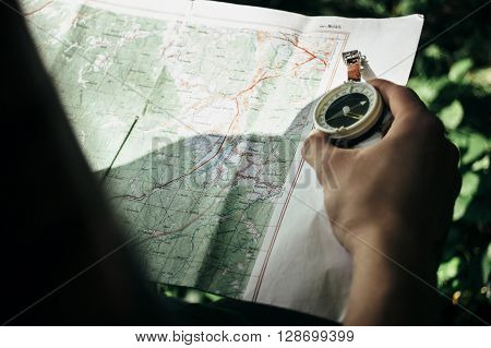 Traveler Exploring Map With Compass In Sunny Forest In The Mountains